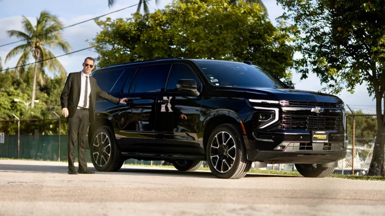 ART chauffeur standing beside a black Suburban