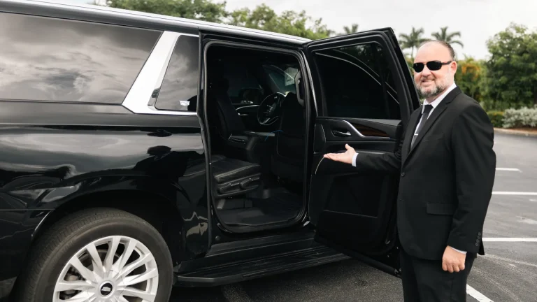 ART chauffeur in a black suit holding open the rear door of a black SUV