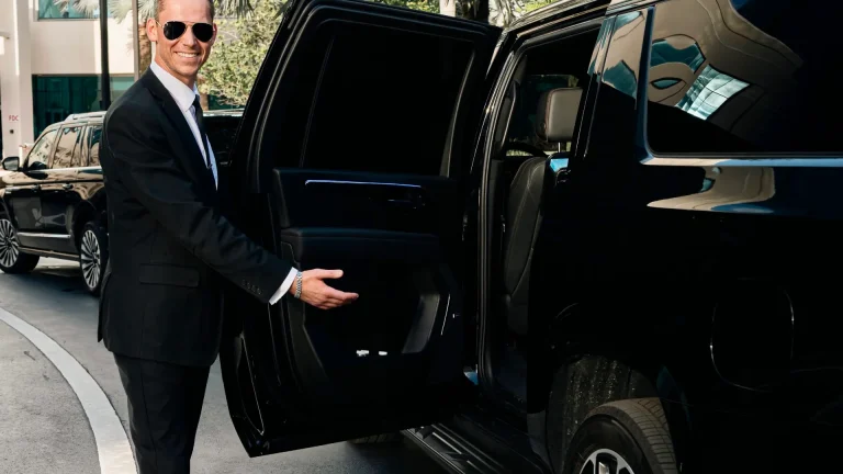 Chauffeur opening the rear door of a black SUV