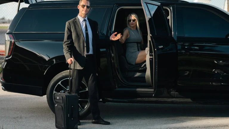 ART chauffeur with a rolling suitcase welcoming a passenger seated in a black SUV