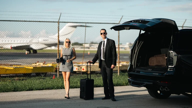 Couple with luggage beside a black Suburban and a private jet