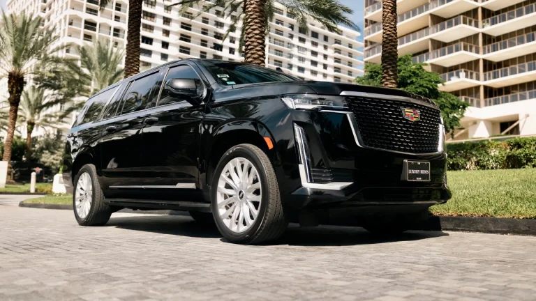 Black Cadillac Escalade parked outside a high-rise condominium with palm trees