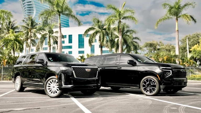 Black Cadillac Escalade and Chevrolet Suburban parked side by side under palm trees