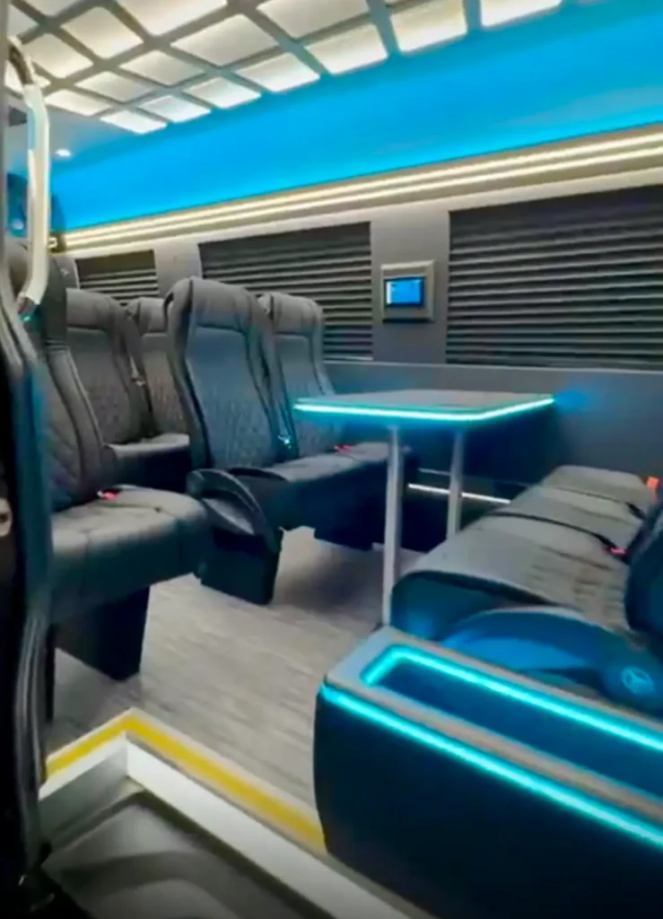 Executive Sprinter interior with leather seats, a table and blue ambient lighting