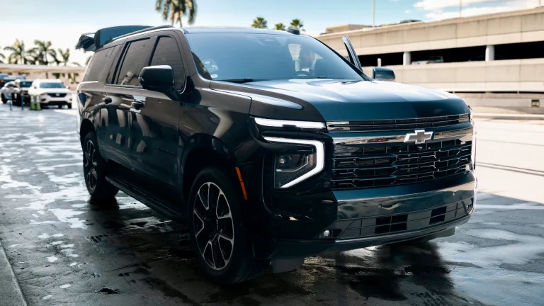 Black Chevrolet Suburban parked beside a parking garage after rain