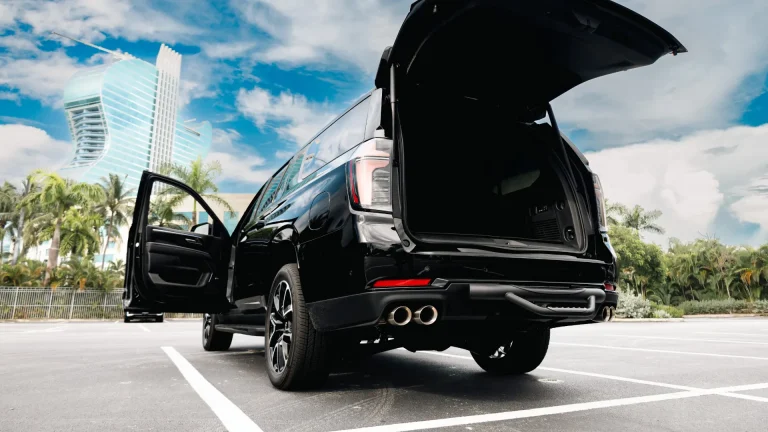 Black Suburban with the rear hatch and door open, ready for luggage