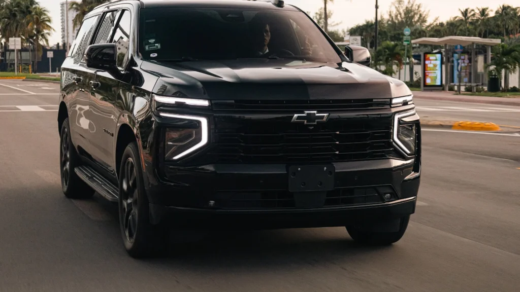 Black Chevrolet Suburban luxury SUV driving toward the camera on a city road