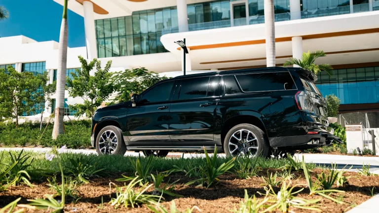 Black Chevrolet Suburban parked beside a modern terminal building with palm trees
