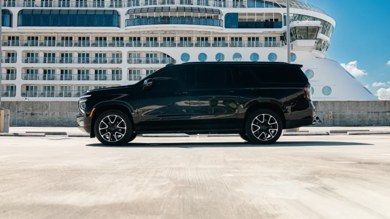 Black Suburban parked on the pier beside a docked cruise ship