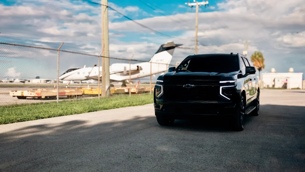 Black Suburban waiting on a private aviation ramp with jets behind it