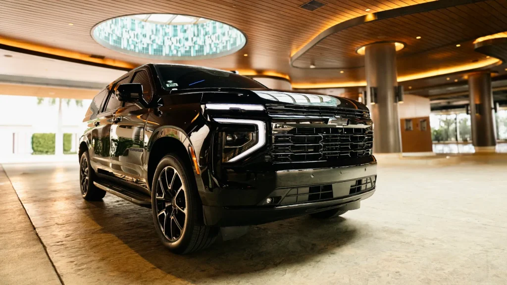 Black Chevrolet Suburban RST waiting under a lit hotel canopy