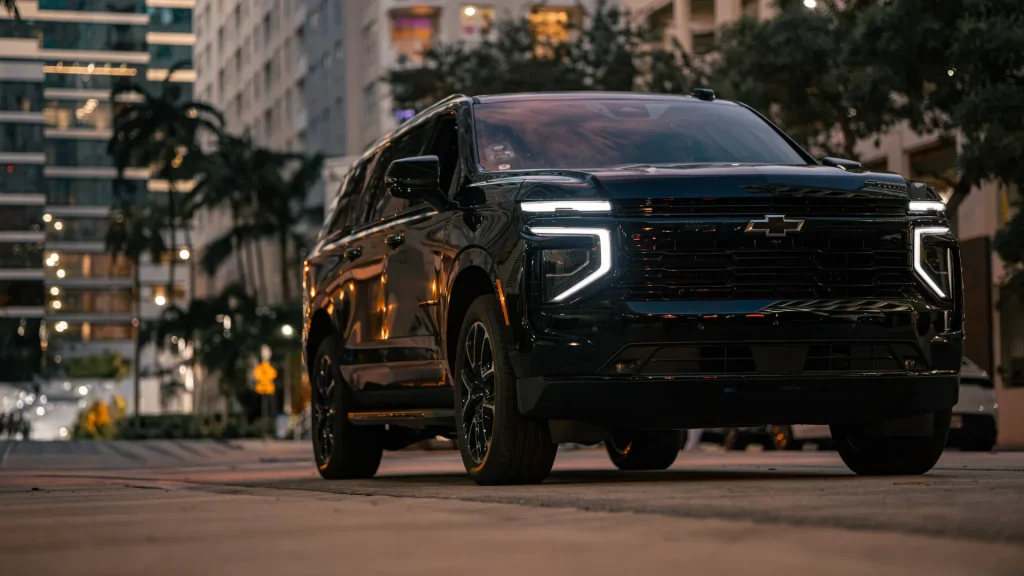 Black Chevrolet Suburban with LED headlights on a Brickell street at night
