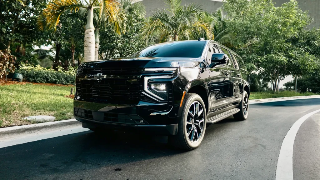 Black Chevrolet Suburban in a tropical, palm-lined driveway