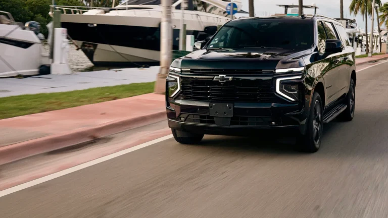 Black Suburban driving past yachts on a waterfront road