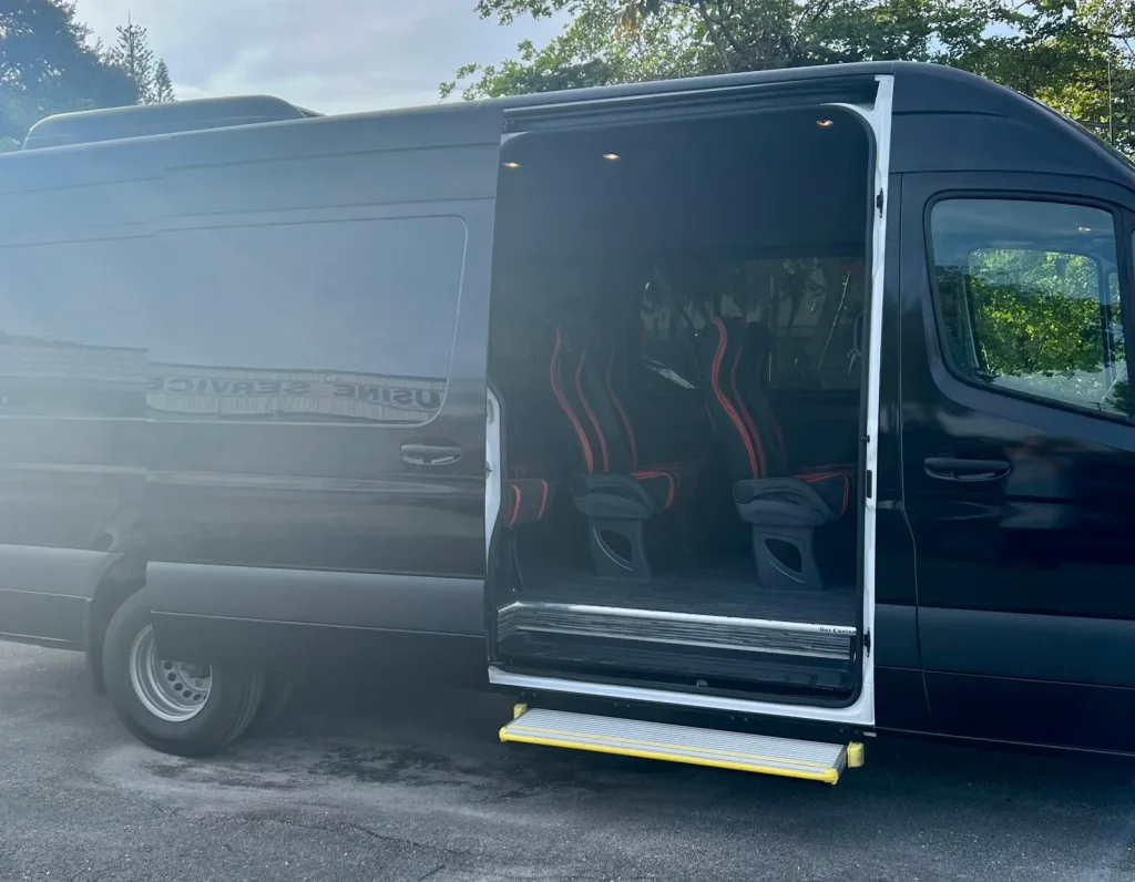 Side door open on a black passenger van with red seats
